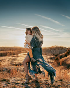 Family Photographer, mother holds daughter in her amrs as she walks through desert