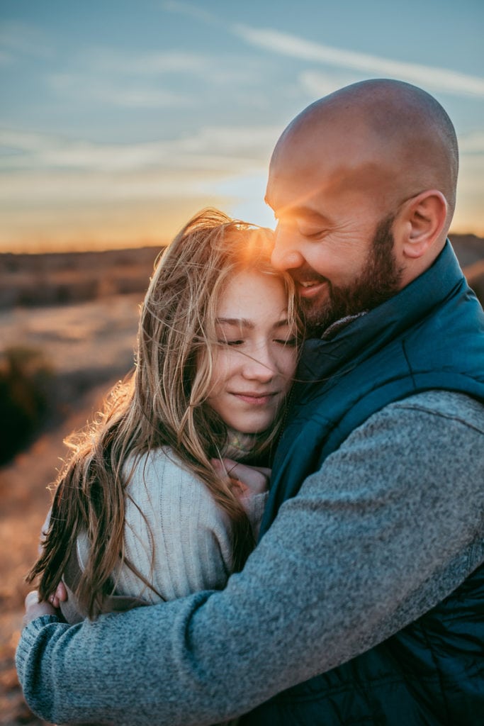 Family Photographer, Dad and daughter embrace outdoors at sunset